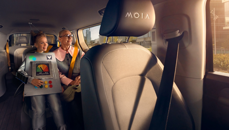 Ein Mädchen im Roboterkostüm und ihre Oma sitzen auf dem Rücksitz eines selbstfahrenden VW ID. Buzz.