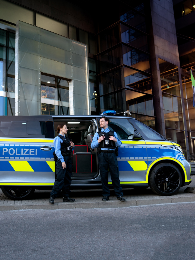 Zwei Polizisten stehen vor einem VW ID. Buzz mit Umbau zum Einsatzwagen.