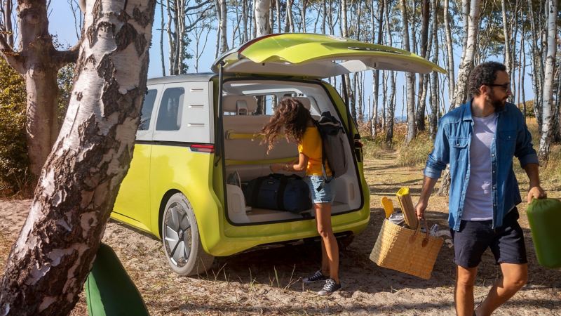 The Volkswagen ID. Buzz stands in the beach forest and is unloaded.