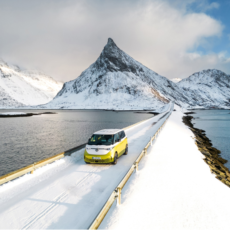 Ein VW ID. Buzz fährt an einer verschneiten Berglandschaft vorbei.