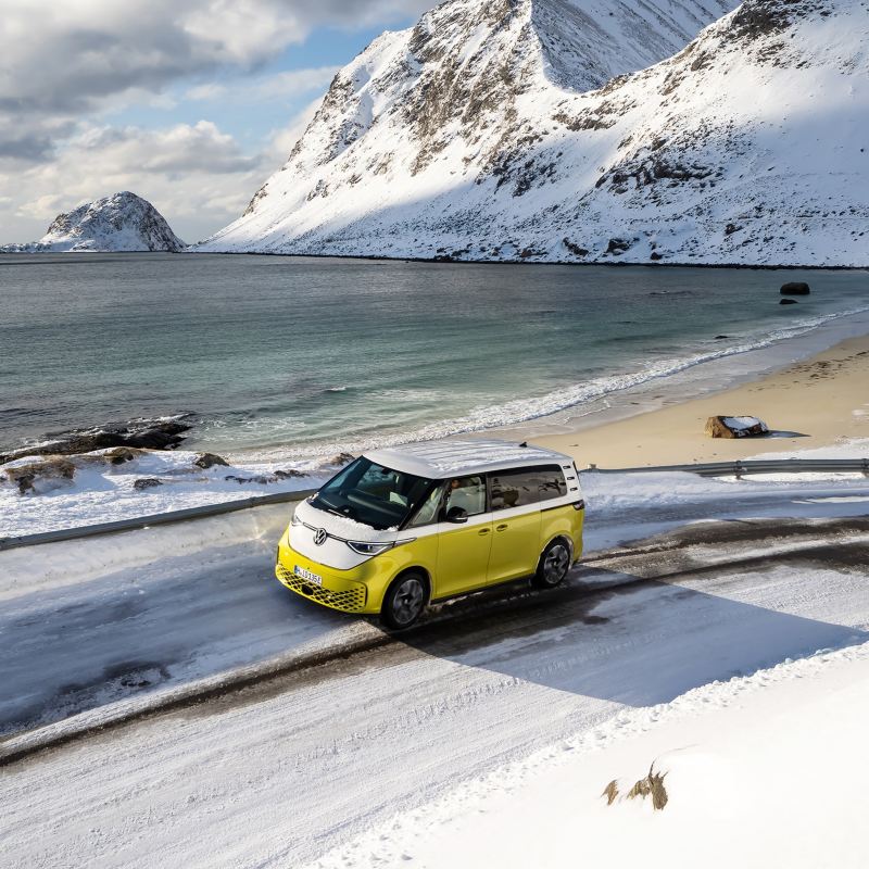 Ein VW ID. Buzz fährt an einer verschneiten Küstenlandschaft vorbei.