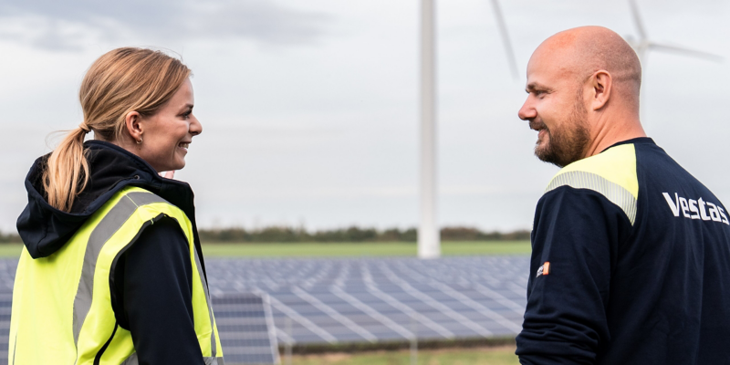 Die Moderatorin spricht mit dem Service-Techniker vor dem Hintergrund der Solarpaneele.