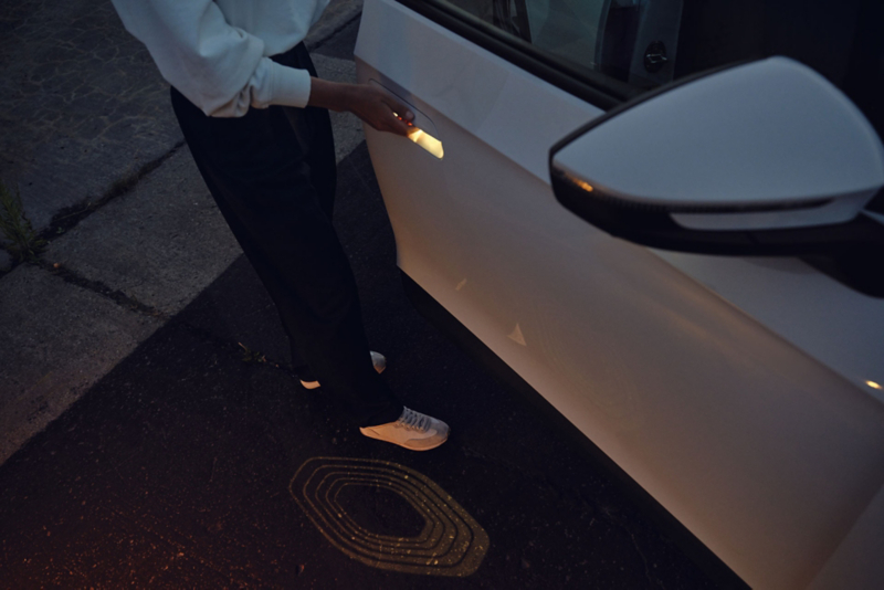 Vue détaillée d'une porte ouverte de la VW ID.4 blanche avec le renfoncement de la poignée de porte éclairé. 