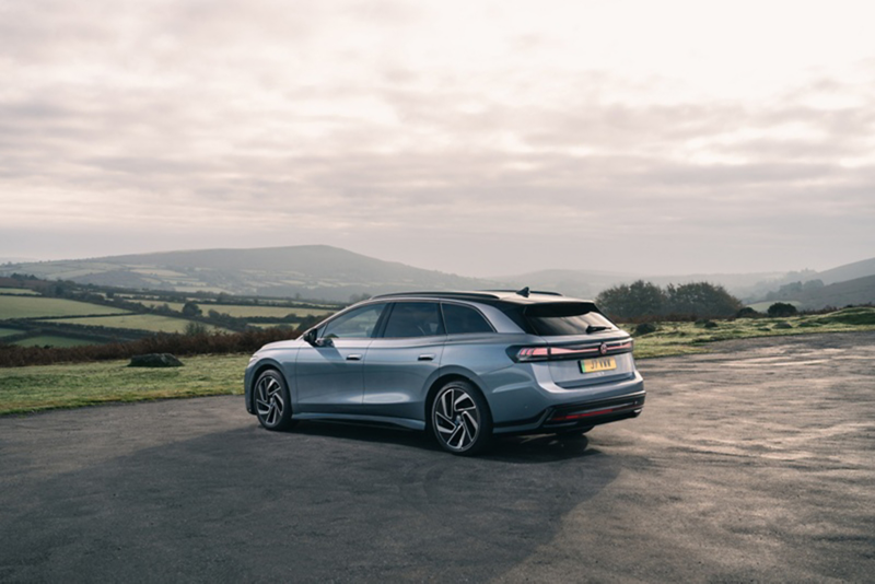 A grey ID.7 Tourer parked near a field with a mountain in the background.