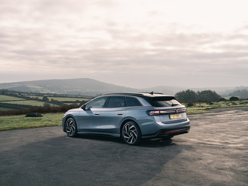 An ID.7 Tourer parked near a field with a mountain in the background.