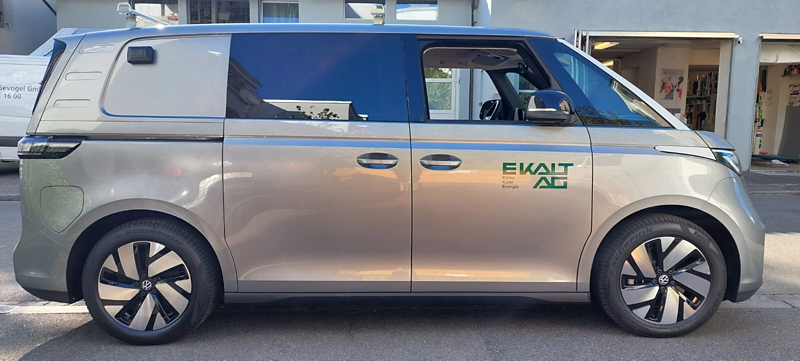 Seitenansicht eines silbernen Volkswagen ID. Buzz mit EKALT-AG-Beschriftung vor einem Firmengebäude.