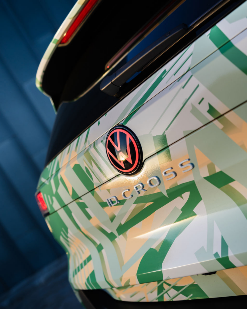 Close-up of the ID. Cross boot with a geometric green and beige camo pattern. A red and black logo and "ID. CROSS" text are visible, set against a modern background.