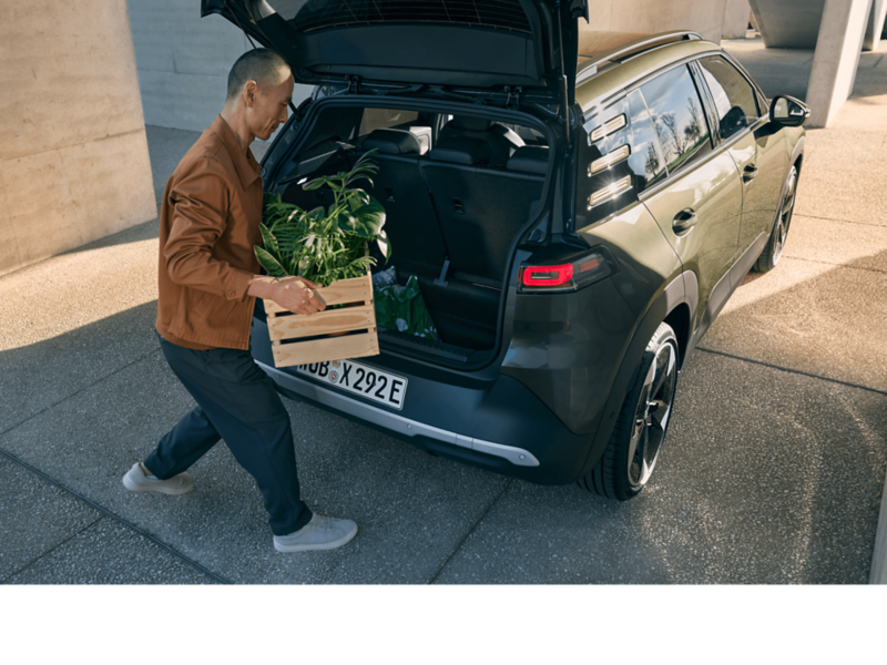 A man loading a box into the back of a VW ID. Cross.