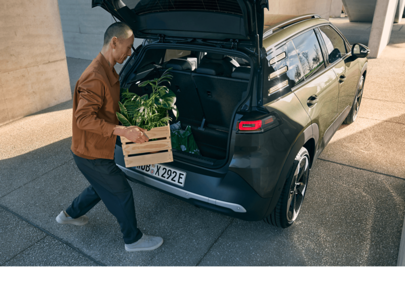 A man loading a box into the back of a VW ID. Cross.