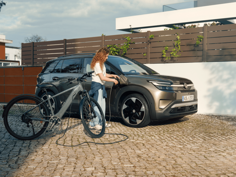 A woman is plugging a charging cable into a VW ID. Cross.