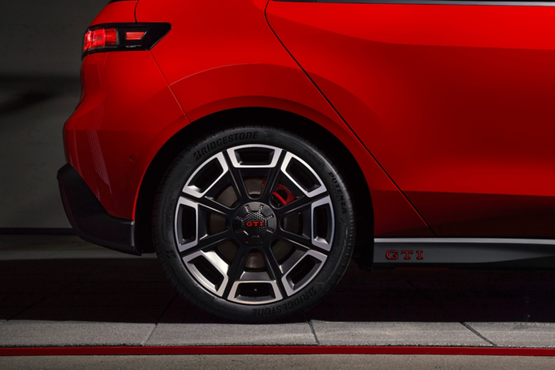 Close-up of the rear wheel and side skirt of a red Volkswagen ID. Polo GTI, showcasing the black and silver sporty rim with a GTI center cap and Bridgestone Potenza tire.