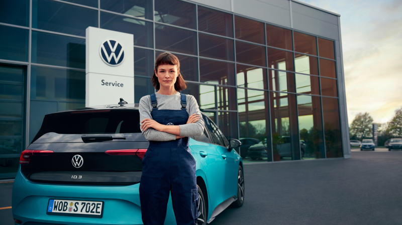 En kvinde står foran en ID.3 parkeret foran en VW forhandler