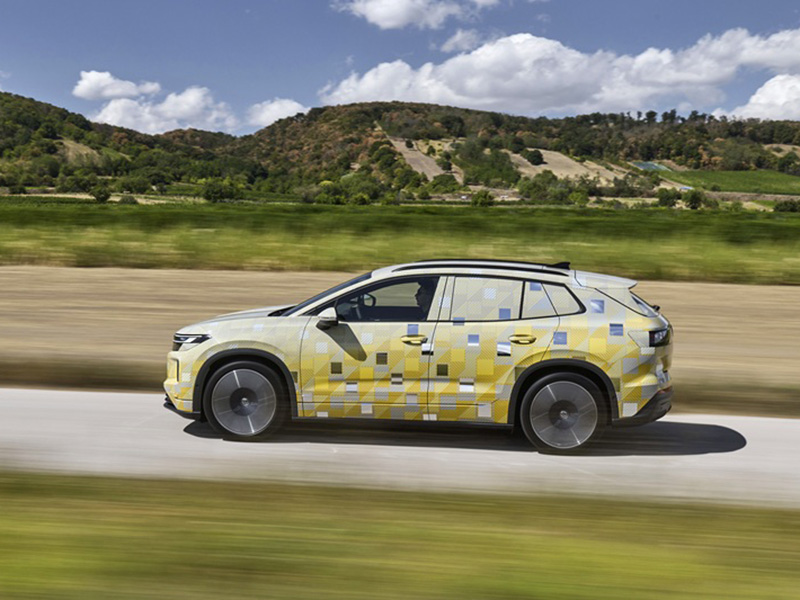 A yellow ID. Tiguan driving down a country road with a sandy hill in the background.