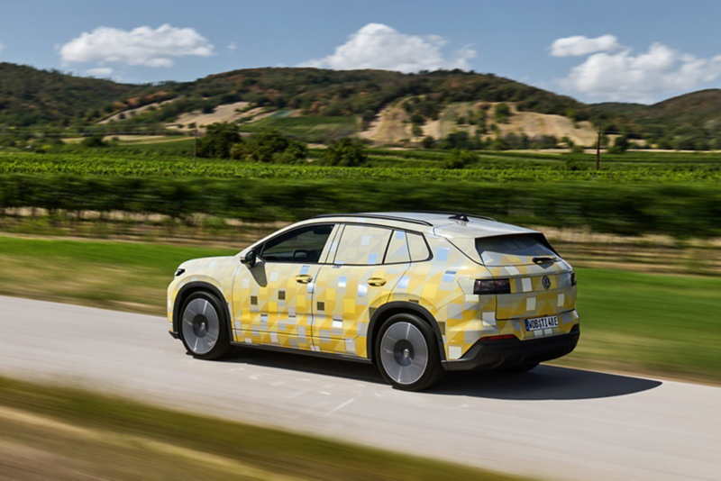 A yellow ID. Tiguan driving down a country road with hills in the background.