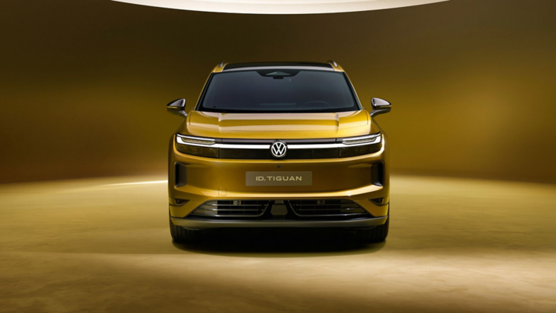 Frontansicht des goldfarbenen Volkswagen ID. Tiguan mit LED-Lichtsignatur und beleuchtetem Volkswagen Logo.