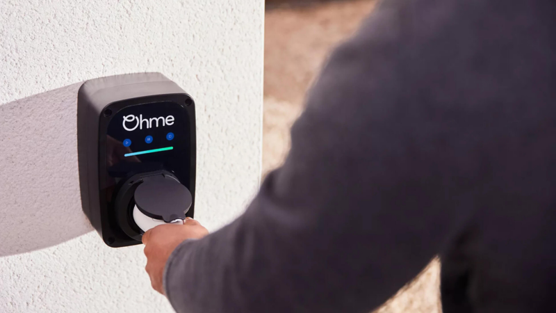 a person grabbing the ohme wallbox charger to charge their VW electric car