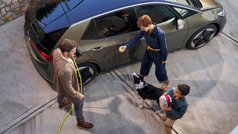 ariel view of people standing next to an olive green ID.3 whilst it is plugged in and charging