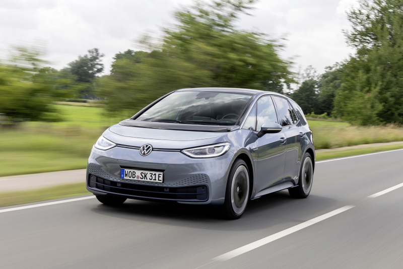 En VW ID.3 kör längs en väg. Grön natur i bakgrunden