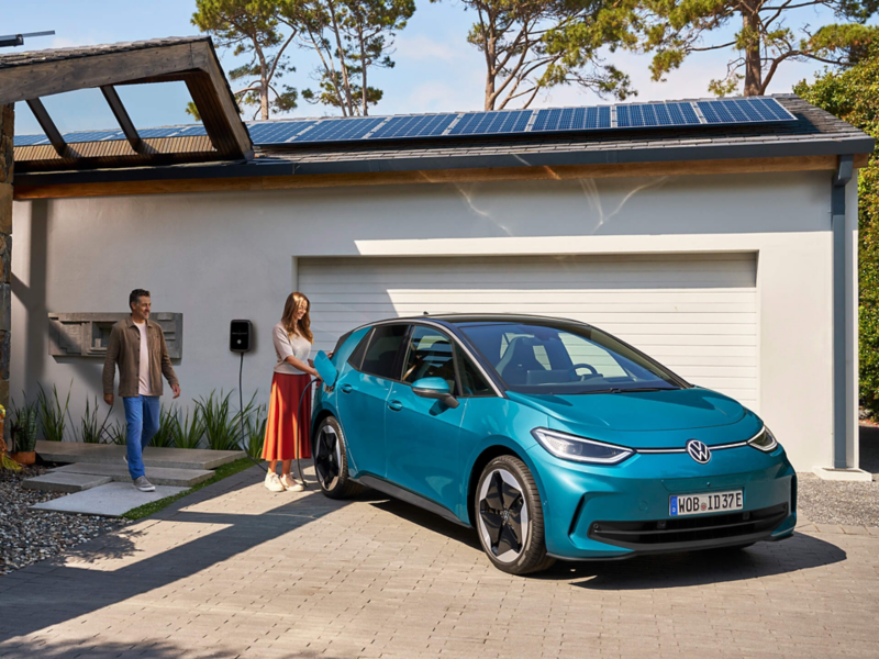 A woman plugging a charger into a green VW ID.3