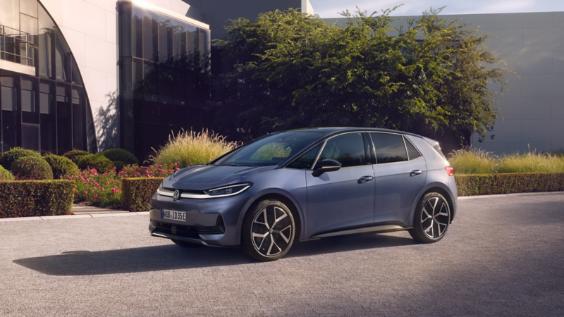 Niebieski VW ID.3 Neo stoi przed budynkiem biurowym ze szklaną fasadą - widok pod kątem od przodu.