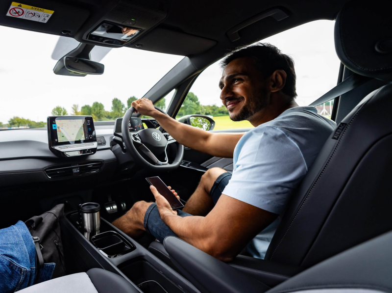 Interior view of a VW cockpit with a man inside holding the steering wheel. 