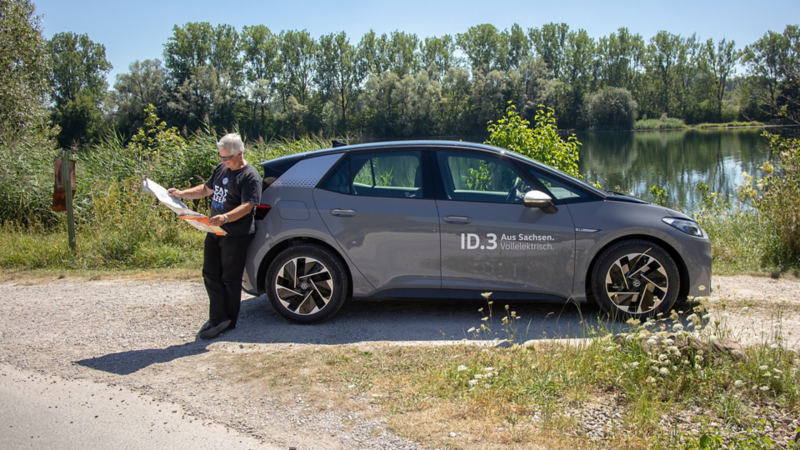 Mann (Felix Egolf) lehnt sich hinten an den ID.3 an