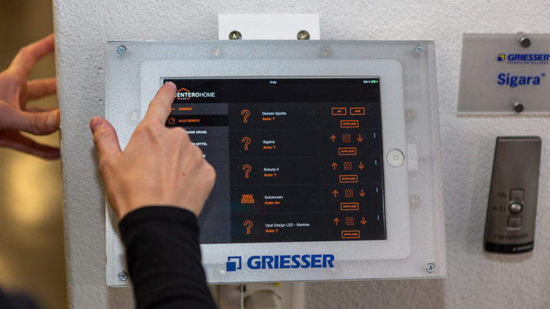 Display für die Steuer der Sonnenschutzanlage von Griesser und eine Frau tippt gerade darauf
