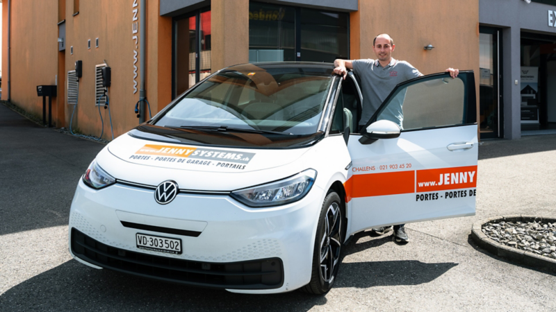 Nicolas Follonier è accanto alla sua VW ID.3 e guarda in direzione della telecamera.