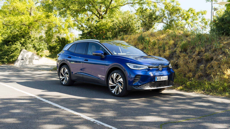 a blue ID.4 driving along a tree lined road