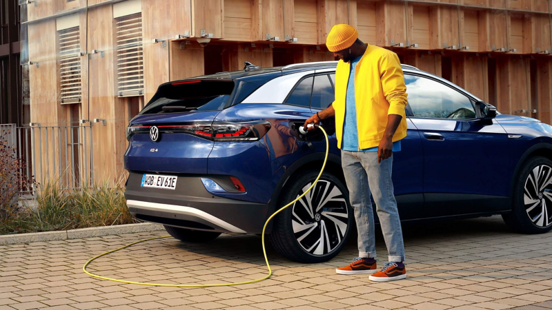 Photo showing a man plugging a VW car into a charging station. 
