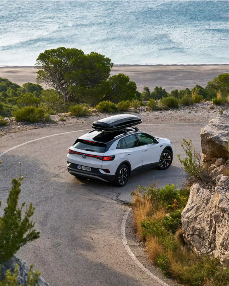 White VW ID.4 driving on coastal highway.