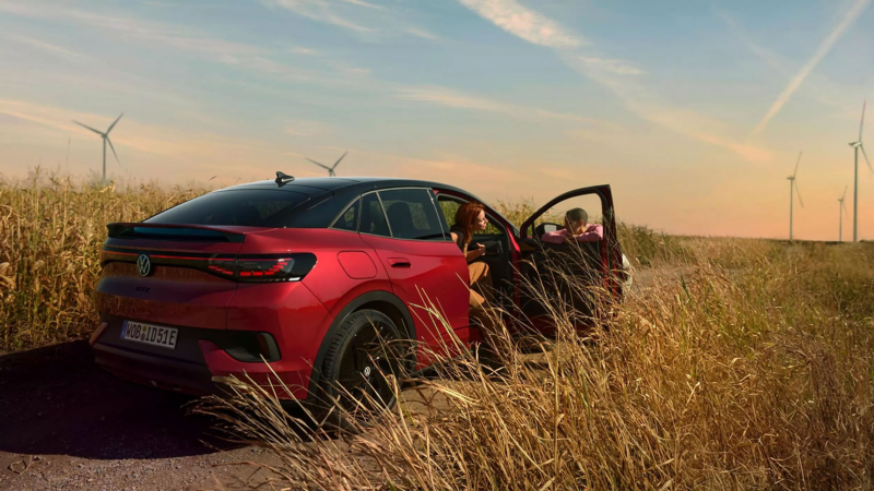 a red ID.5 parked in a golden corn field with wind turbines in the distance