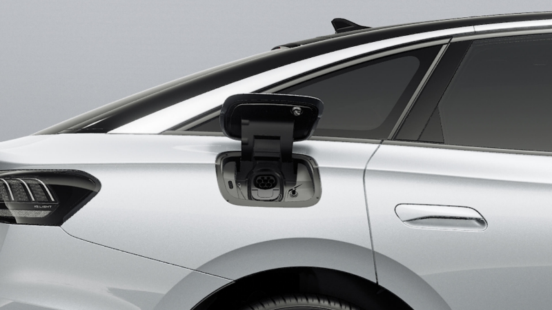 Close-up of a silver Volkswagen ID.7 showing the side charging port. The charging socket is open, and the car's sleek design is visible, highlighting modern technology.
