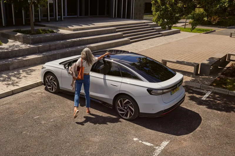 ID.7 staat geparkeerd in een parkeervak, een vrouw haalt haar beker van het dak