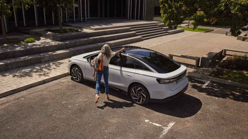 Photo showing a woman standing next to a parked VW ID.7. 