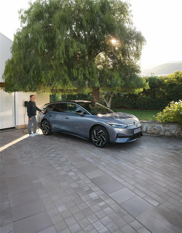 A VW ID.7 is parked on the terrace in front of a house. Side view of the vehicle.