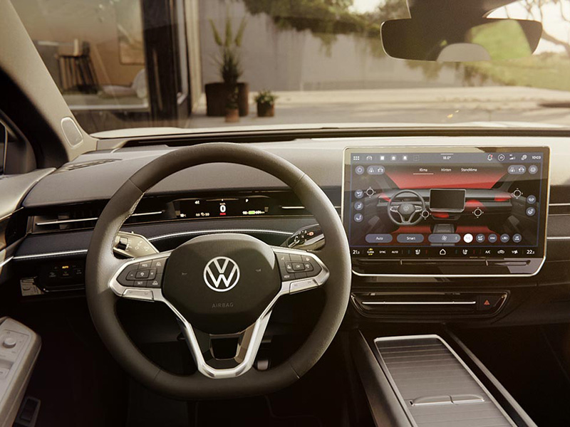 Interior view of a Volkswagen car showing the steering wheel, digital dashboard, and central infotainment screen with ambient blue door lighting.