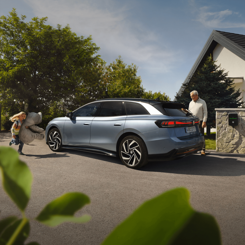 Szare ID.7 Tourer ładowany przez mężczyznę na parkingu.