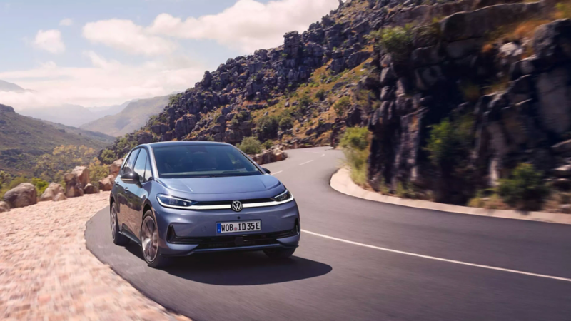 Une VW ID.3 Neo bleue roule sur une route de montagne sinueuse.