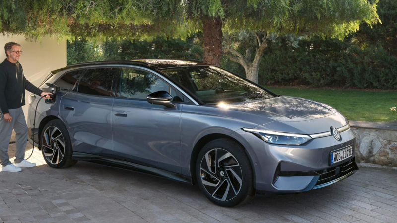 A person charging an ID.7 Tourer parked on a concrete driveway