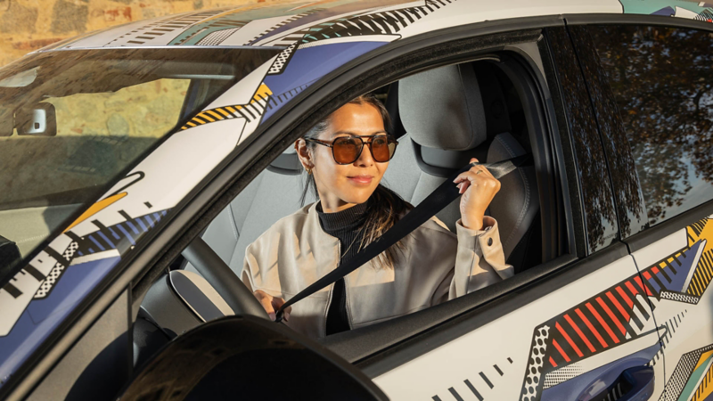 Fahrerin sitzt im Volkswagen ID. Polo und legt den Sicherheitsgurt an.