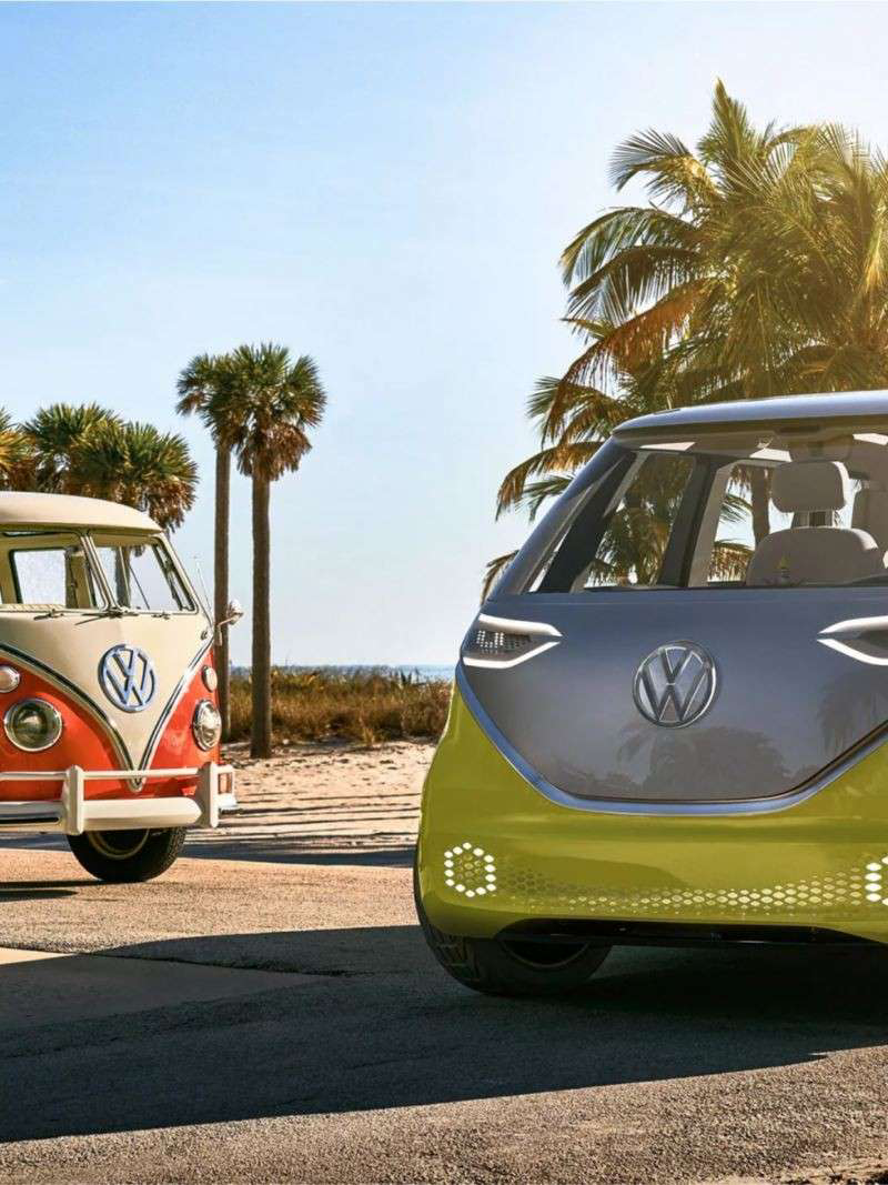 ID.Buzz next to VW camper van at the beach.