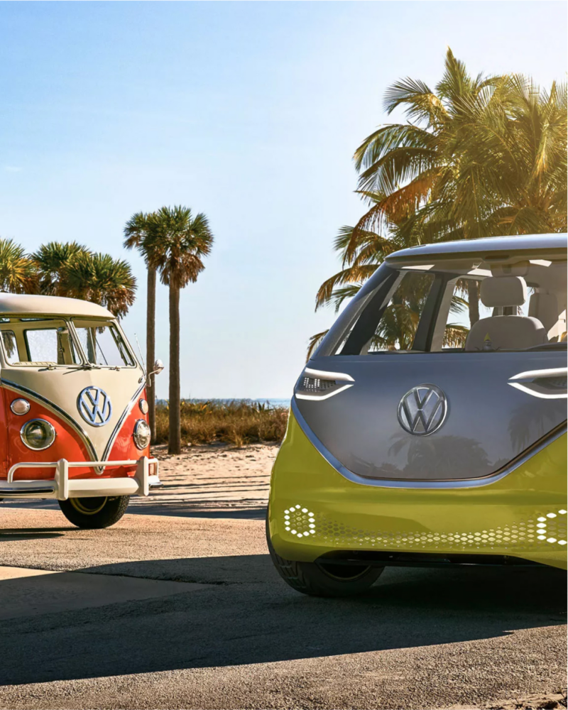 ID.Buzz next to VW camper van at the beach.