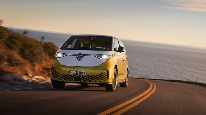 The yellow Volkswagen ID. Buzz driving on the road near the ocean