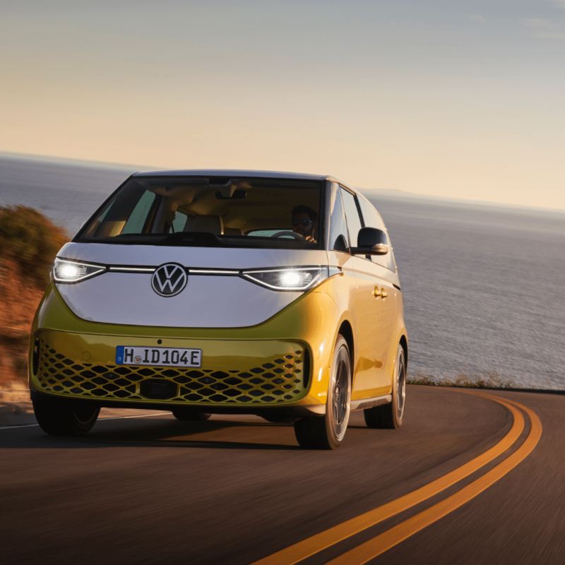The yellow Volkswagen ID. Buzz driving on the road near the ocean