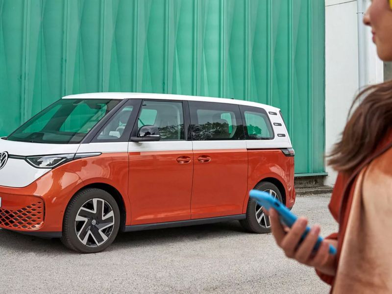 Mujer sentada en un vehículo Volkswagen usando una tableta.