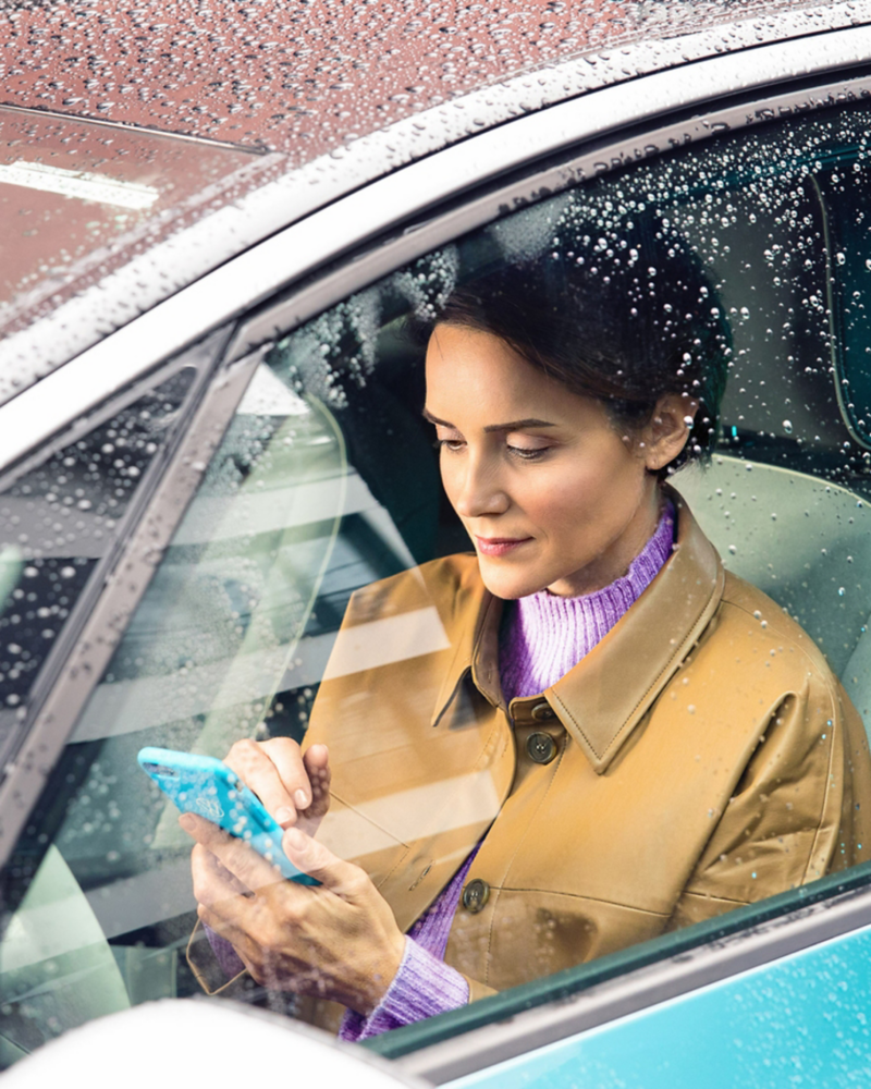 Woman in VW vehicle using mobile phone to request tow service.