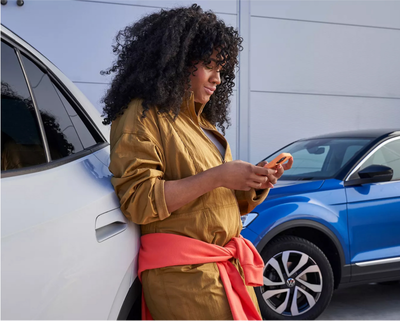 Woman standing beside a Volkswagen.