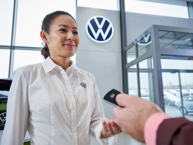 Woman assisting a customer in VW dealership.