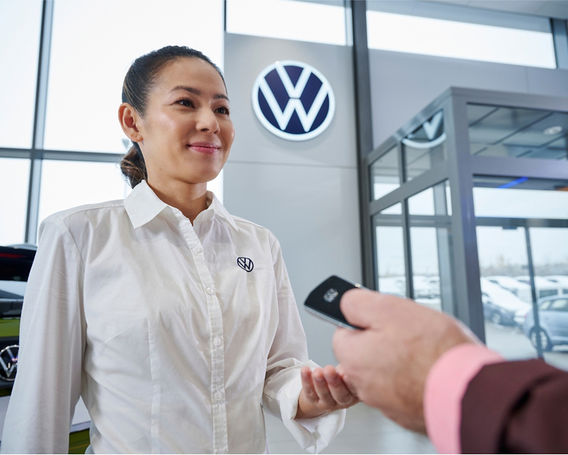 Woman assisting a customer in VW dealership.